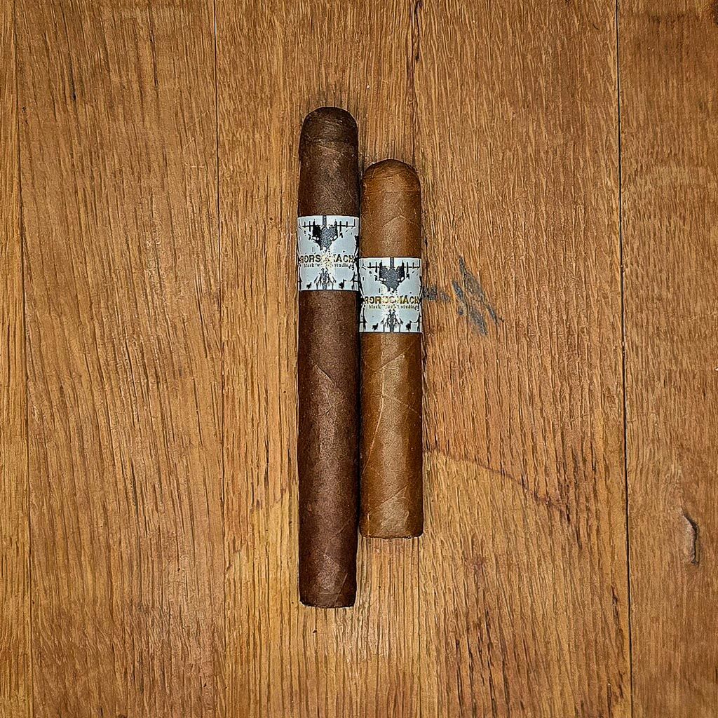BLK WKS Rorschach Sumatra Short Robusto and Toro vitolas side by side on rustic wood surface showing Sumatran wrapper and signature white BLK WKS band