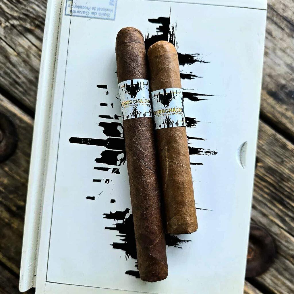 Two BLK WKS Rorschach Sumatra cigars with white and gold band resting on BLK WKS white box lid at Smokers Abbey Austin