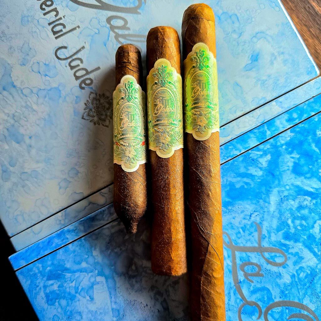 Three La Galera Imperial Jade cigars in Chiquito Perfecto, Robusto, and Churchill vitolas resting on the blue marbled Imperial Jade box showing African Cameroon wrapper and iridescent green La Galera band at Smokers Abbey Austin.