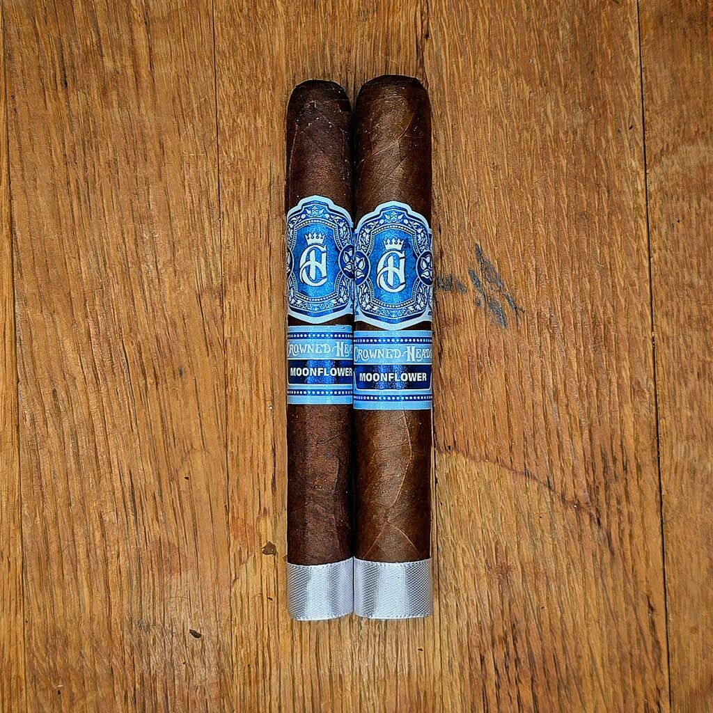 Crowned Heads Moonflower Corona Gorda and Toro cigars displayed side by side on rustic wood surface showing dark Nicaraguan Corojo wrapper and blue and silver Moonflower band at Smokers Abbey Austin Caption: