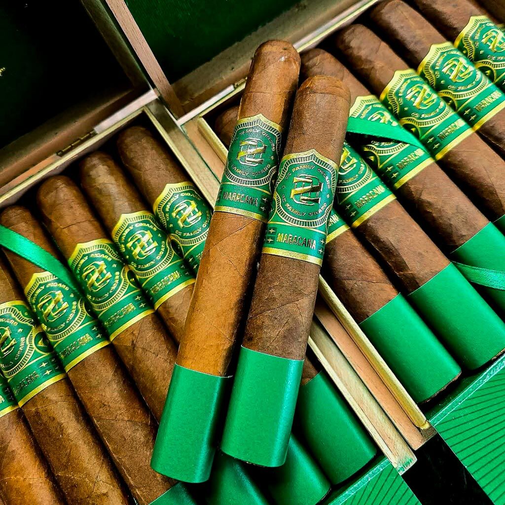Ozgener Maracana box pressed cigars resting across open 21-count green cedar box showing Brazilian Arapiraca wrapper and bold green and gold Maracana band in the humidor at Smokers Abbey Austin