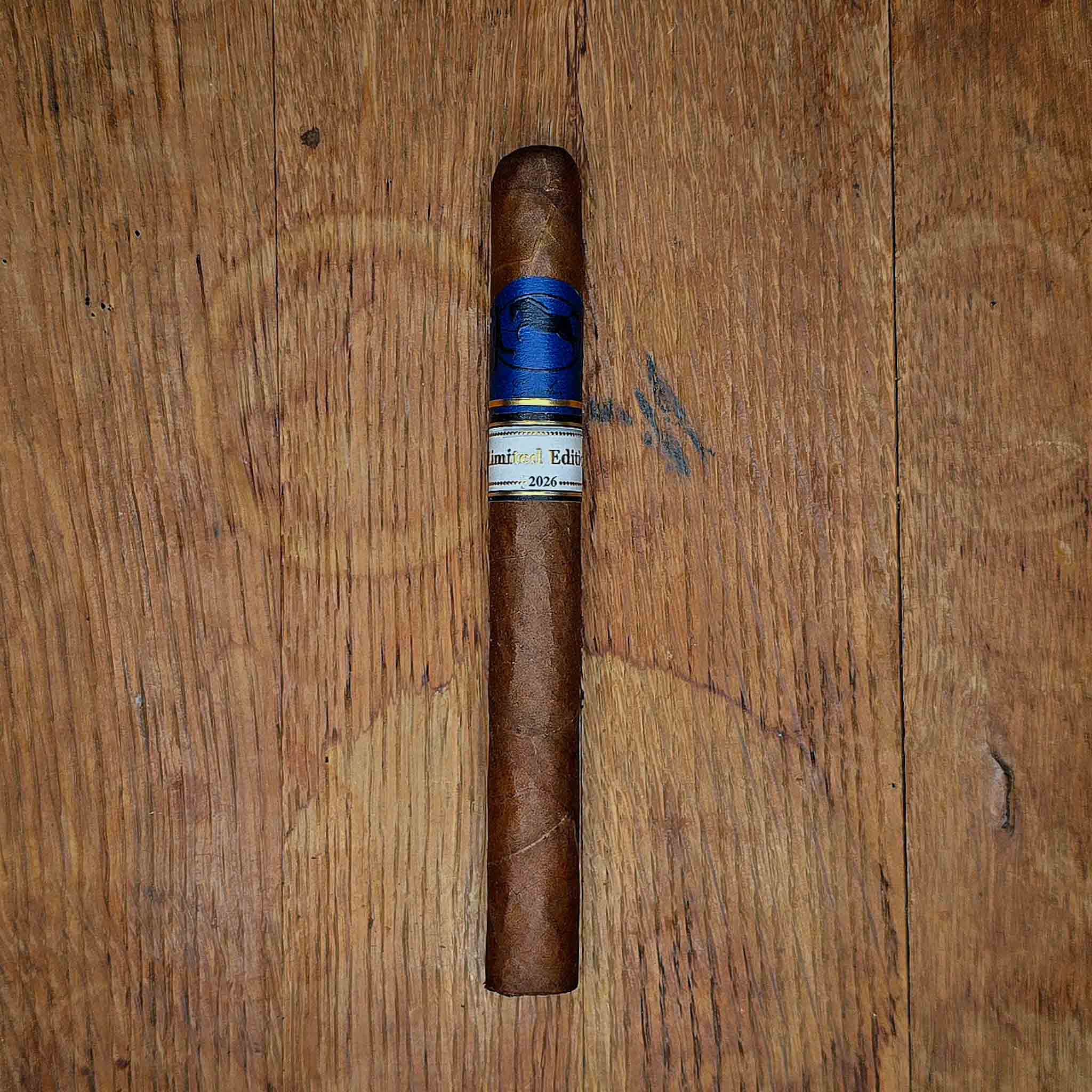 Cavalier Genève Limited Edition 2026 cigar with blue Cavalier band and ivory Limited Edition 2026 band resting in a cutout of rustic wood at Smokers Abbey Austin