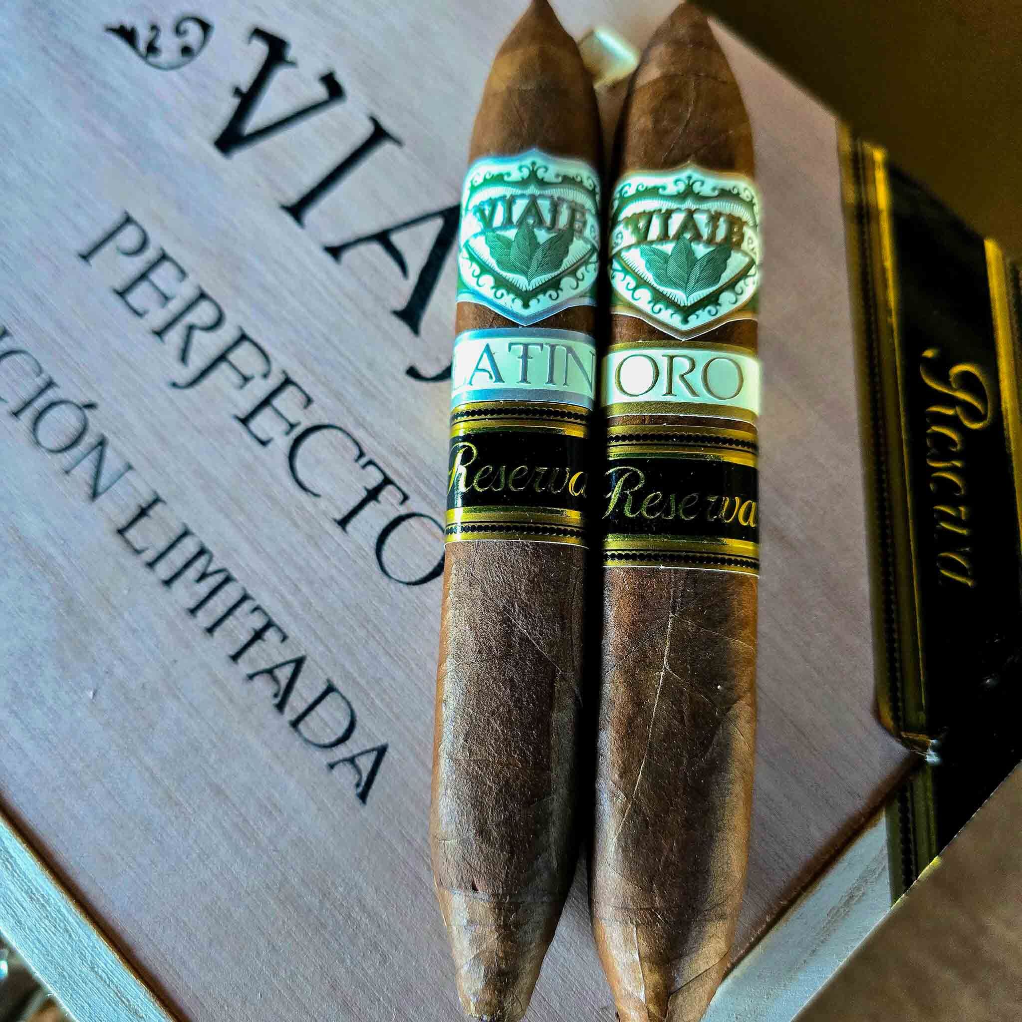 Viaje Perfecto Reserva Platino and Oro cigars leaning together against a Viaje wooden box lid marked Perfecto Region Limitada at Smokers Abbey Austin