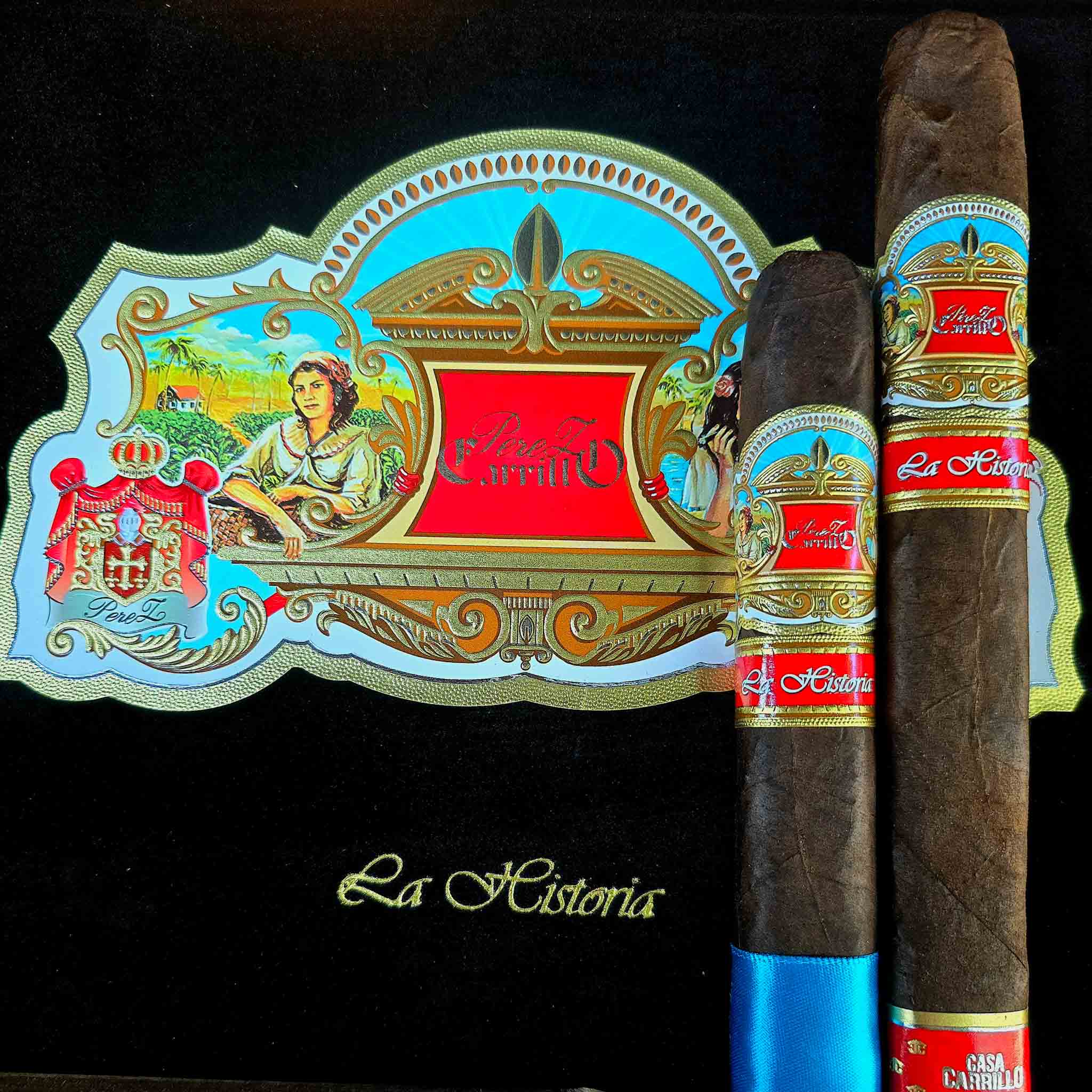 Casa Carrillo La Historia El Senador and E-III cigars standing upright against the open black and gold La Historia box with ornate Perez Carrillo artwork at Smokers Abbey Austin