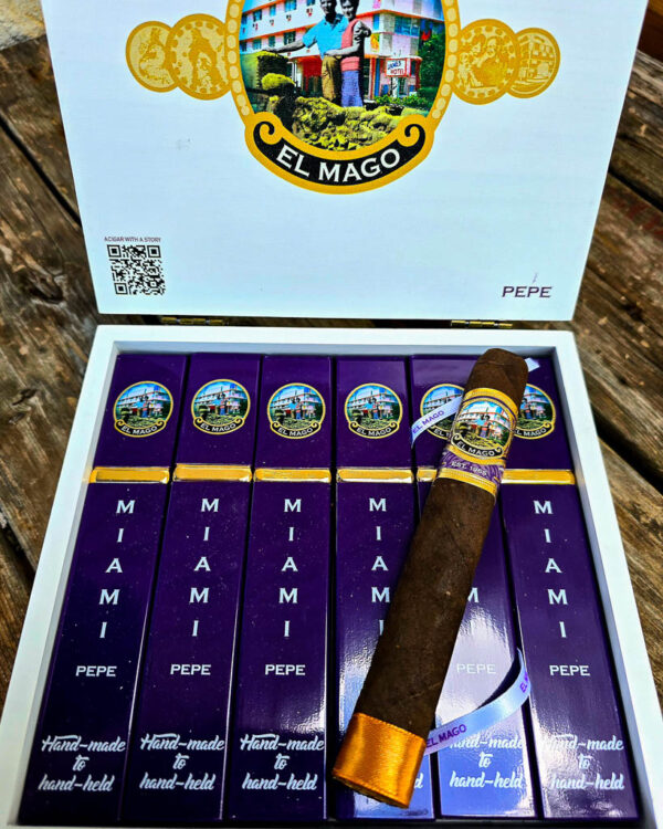 An open box of El Mago Pepe cigars showing purple Miami Pepe-branded tubes, with one box-pressed Toro cigar displayed on top.