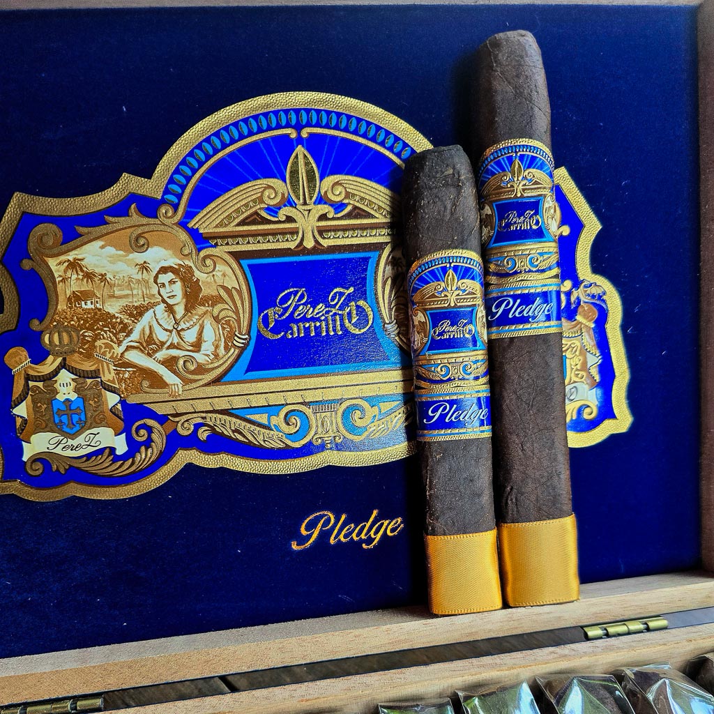 Casa Carrillo Pledge Prequel and Sojourn cigars standing upright against the open navy blue Pledge box with ornate gold Casa Carrillo artwork at Smokers Abbey Austin