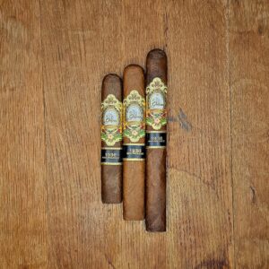 Three La Galera 1936 Box Pressed cigars in Chaveta, El Lector, and Cabeza vitolas displayed side by side on rustic wood surface showing three distinct wrapper shades and ornate gold and black 1936 Box Pressed band at Smokers Abbey Austin