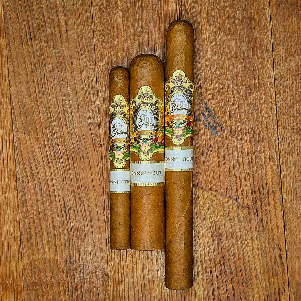 Three La Galera Connecticut cigars in Cepo, Pilone, and Presidente vitolas displayed side by side on rustic wood surface showing Ecuadorian Connecticut wrapper and ornate gold La Galera band at Smokers Abbey Austin
