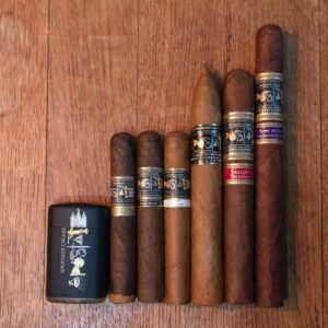Apostate Cigars sampler including Sword of Laban Churchill, Moroni's Trumpet, The Endowment, The Initiatory, The Deseret, Secret Combination, and Apostate lighter displayed on rustic wood surface at Smokers Abbey Austin