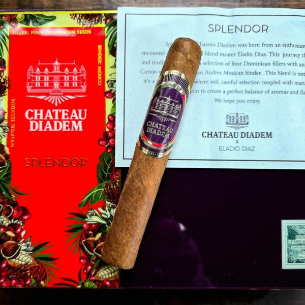 Chateau Diadem Splendor Robusto Extra cigar leaning against the vibrant red Splendor box alongside the Chateau Diadem x Eladio Diaz collaboration card at Smokers Abbey Austin