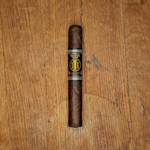 Jake Wyatt Cigar Co. Titan Series Colossus Oscuro Toro cigar with black and gold band displayed on rustic wood surface at Smokers Abbey Austin