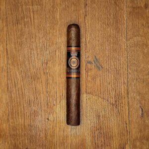 Jake Wyatt Cigar Co. Titan Series Goliad Claro Toro cigar with black and copper target band displayed on rustic wood surface at Smokers Abbey Austin