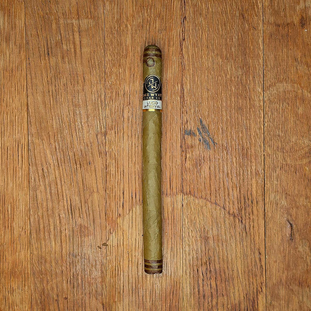 Jake Wyatt Lithium Dominican Lancero cigar with black and gold band displayed on rustic wood surface — the last of the discontinued Dominican Lancero vitola at Smokers Abbey Austin