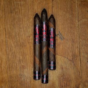 BLTC Bishops Blend 2026 10th Anniversary Robusto, Corona Larga, and Lancero cigars with double Ecuadorian Maduro and Connecticut Broadleaf barber pole wrapper displayed on rustic wood surface at Smokers Abbey Austin