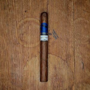 Cavalier Genève Limited Edition 2026 cigar with blue Cavalier band and ivory Limited Edition 2026 band resting in a cutout of rustic wood at Smokers Abbey Austin
