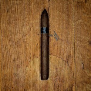 Tatuaje Creature From Tatuaje 6 7/8 x 52 perfecto cigar with black on black Tatuaje band displayed on rustic wood surface at Smokers Abbey Austin