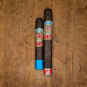 Casa Carrillo La Historia El Senador and E-III cigars with red and gold La Historia band displayed side by side on rustic wood surface at Smokers Abbey Austin