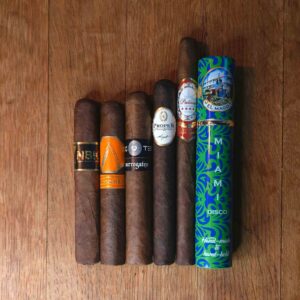Oscuro Sampler featuring BLK WKS Studio NBK, La Barba Ricochet Crü Oscuro, L'Atelier Surrogates Big Ten, Proper by FQ Cigars, Patina Oro de Nicaragua Lancero, and El Mago Disco displayed side by side on rustic wood surface at Smokers Abbey Austin