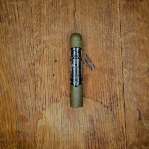 Little Green One candela cigar with black OSOK band featuring a roaring jaguar illustration, displayed on rustic wood surface at Smokers Abbey Austin