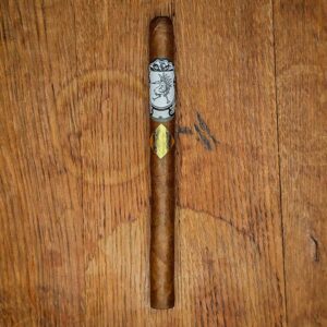 Cavalier Genève Small Batch Lancero with white crest band and gold diamond foil badge on a rustic wood surface at Smokers Abbey Austin